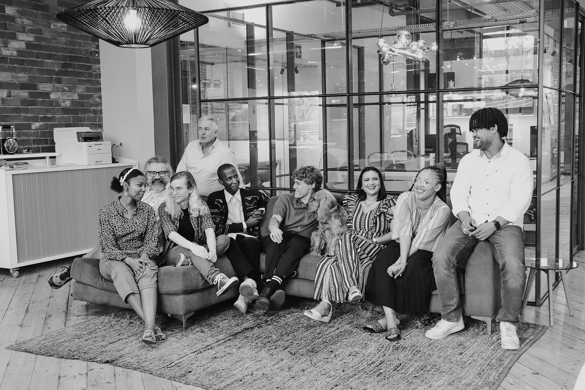 Trinity Iot Service Provider's staff sitting together on a large, rounded sofa in an office environment with modern aesthetics.