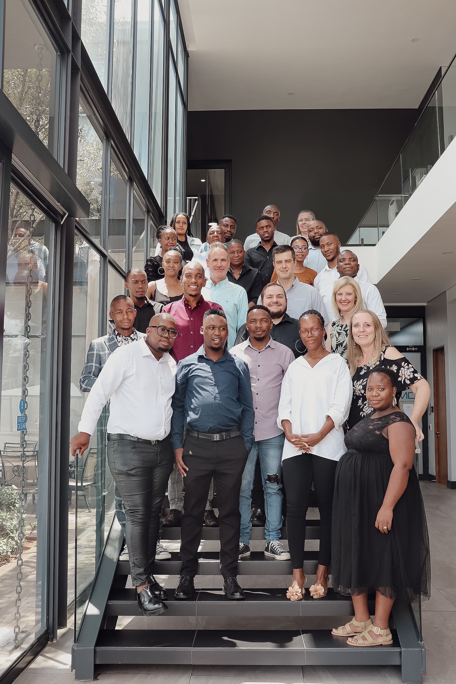 Trinity Iot Service Provider's staff sitting together on a large, rounded sofa in an office environment with modern aesthetics.